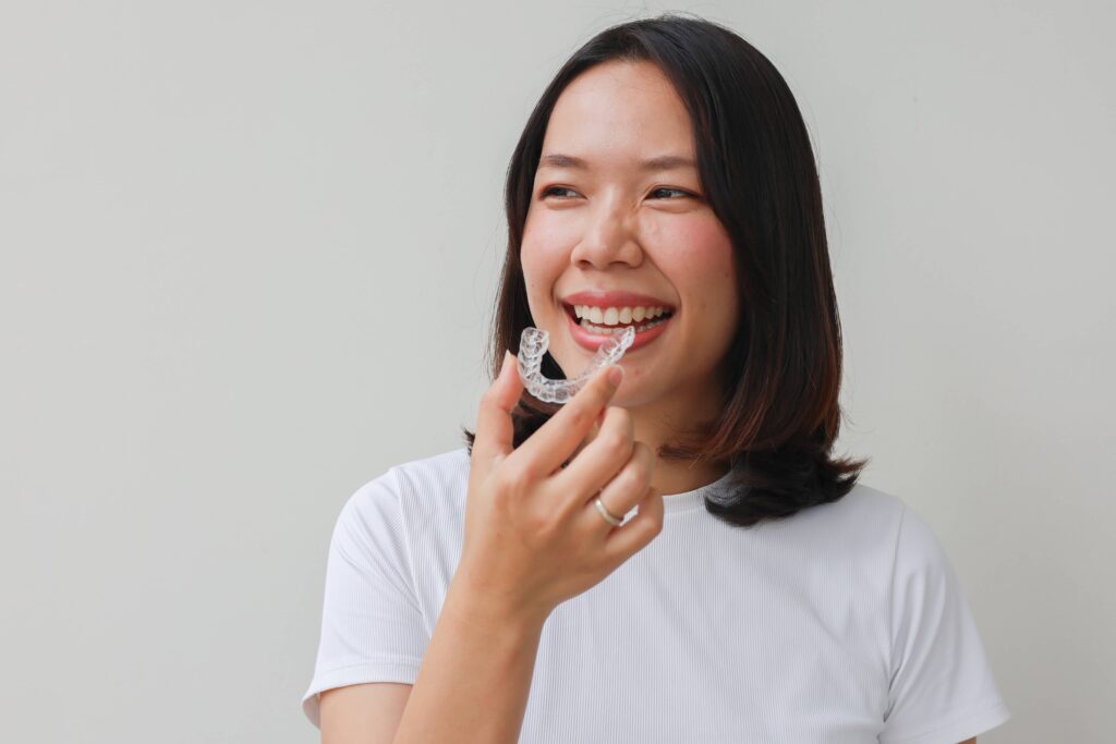 close up young lovely asian woman hand holding dental aligner retainer